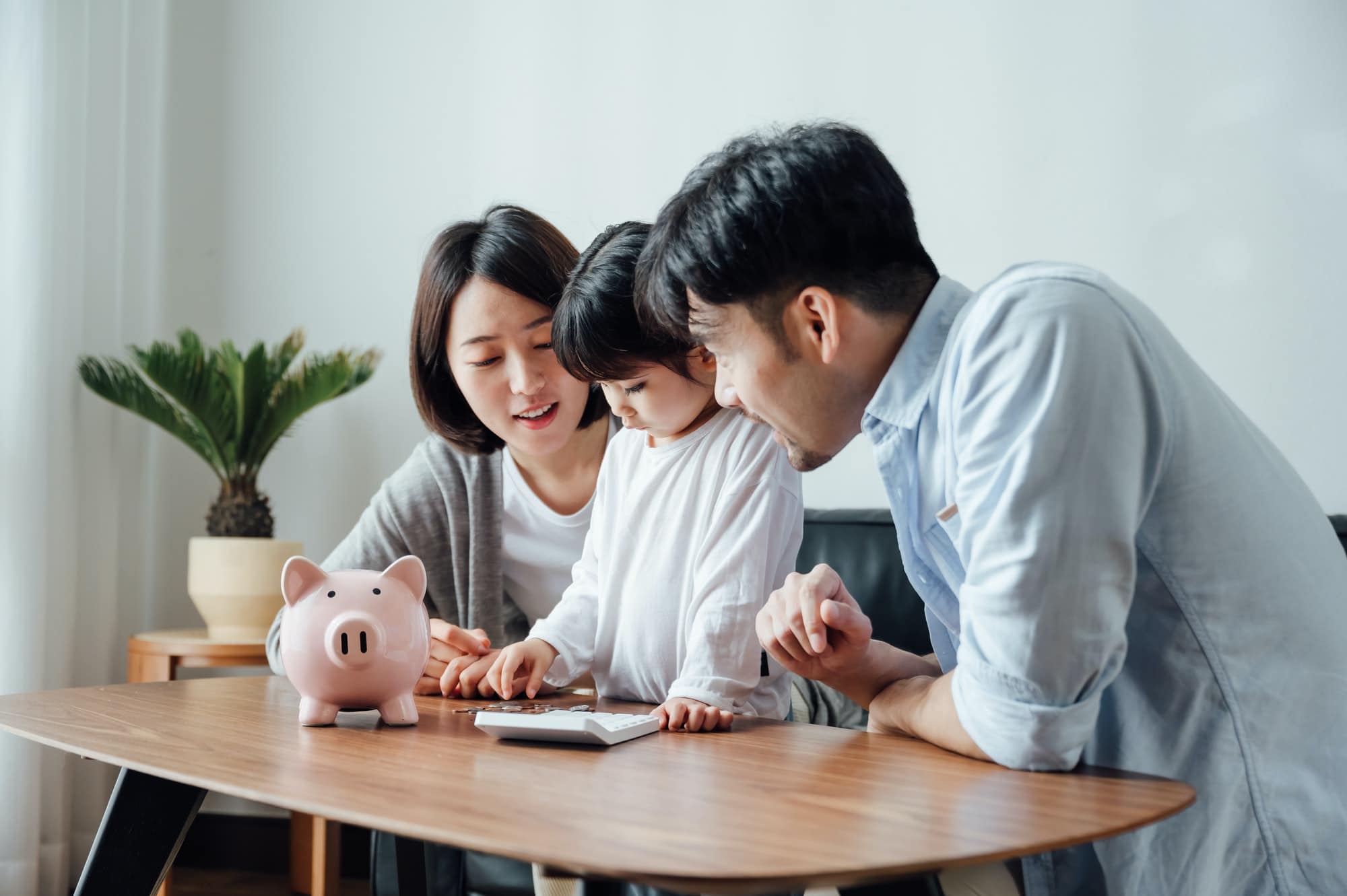 Parents teaching daughter to save money at home