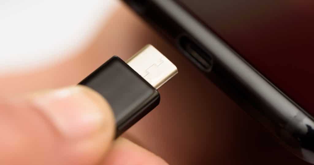 Persons hand inserting a USB cable charger into a mobile phone
