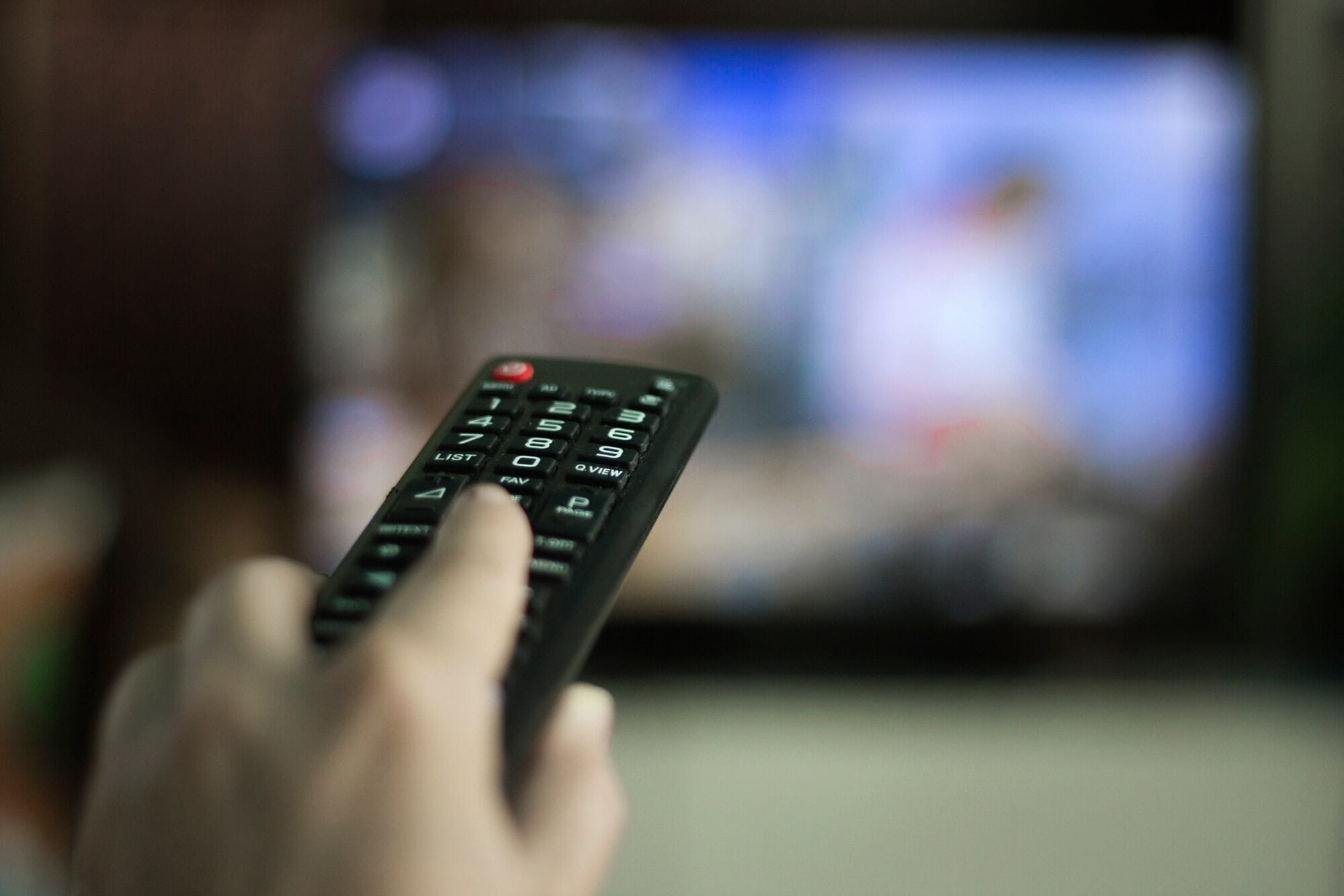 Close up of hand holding tv remote control